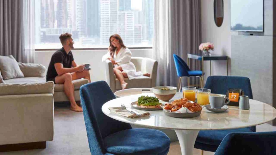 Couple Sitting In Hotel Room with Breakfast on Table