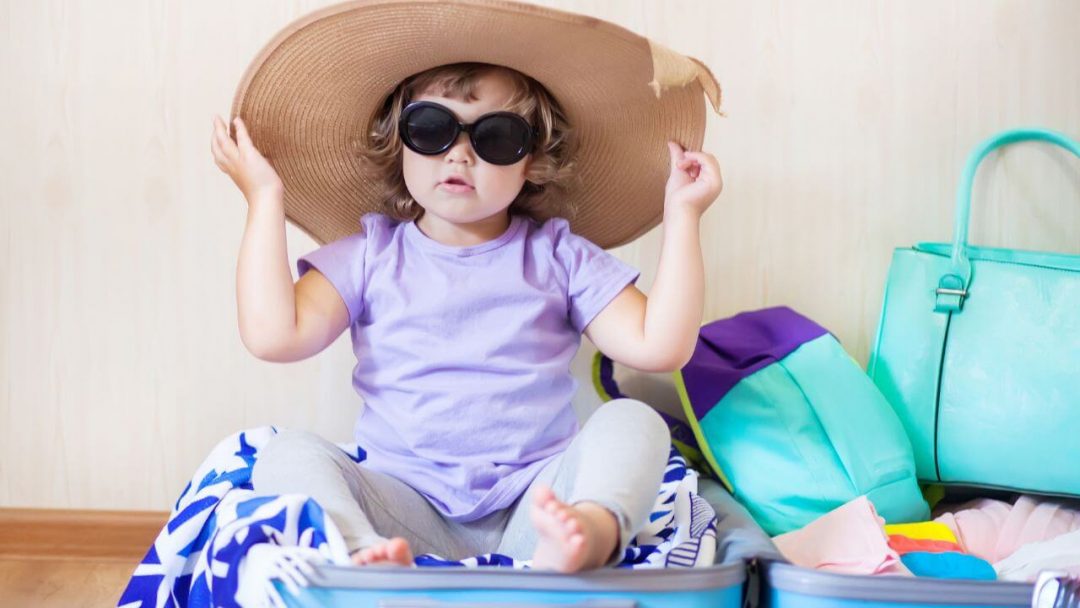 Girl wearing hat and shades in suitcase